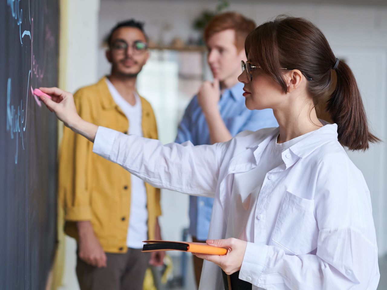 Une formatrice explique une notion au tableau